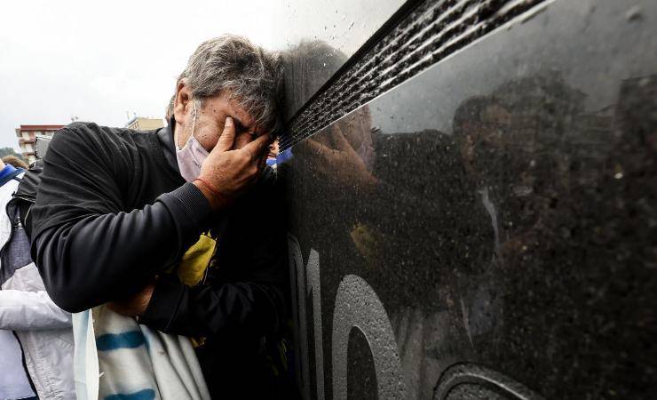 Un tifoso piange sotto la statua di Maradona 